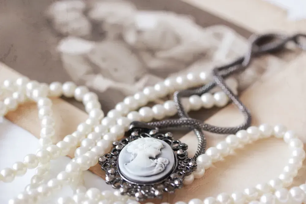 Victorian cameo and pearl necklace in front of vintage picture.