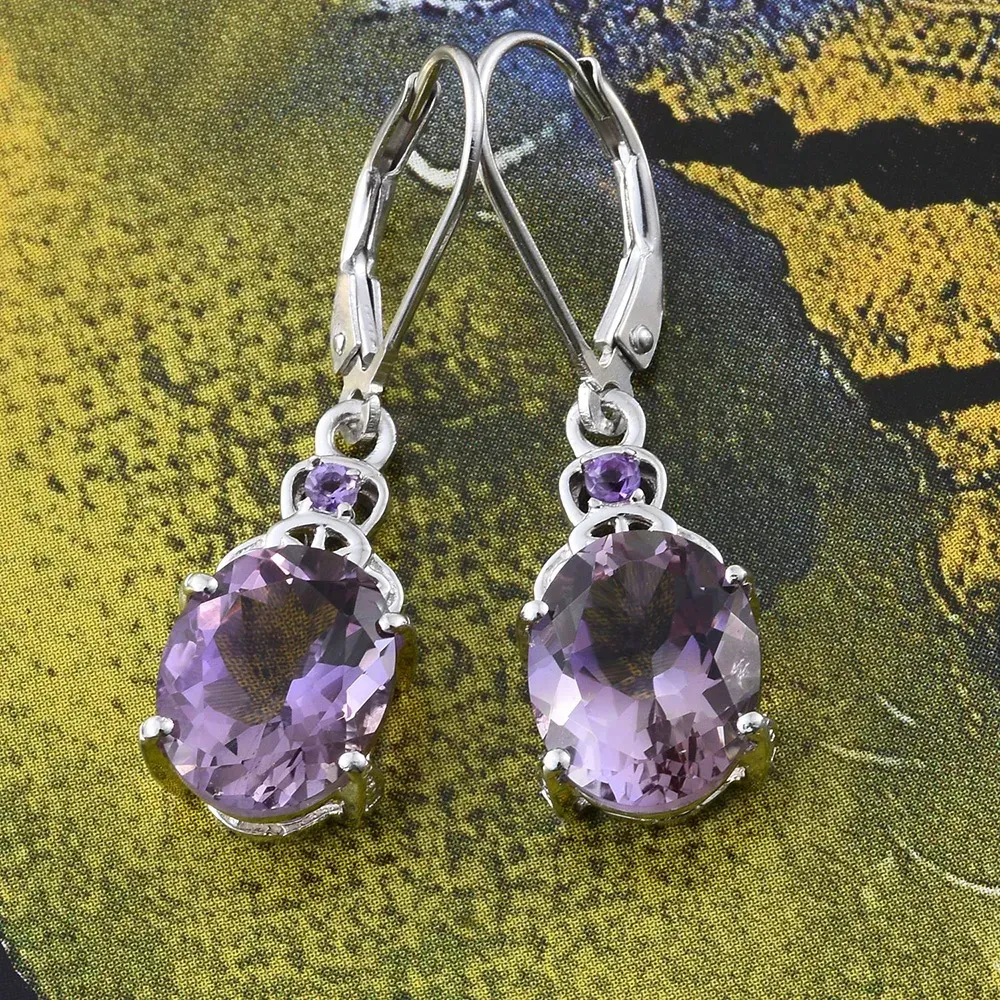 Pair of ametrine earrings against green and yellow fabric.
