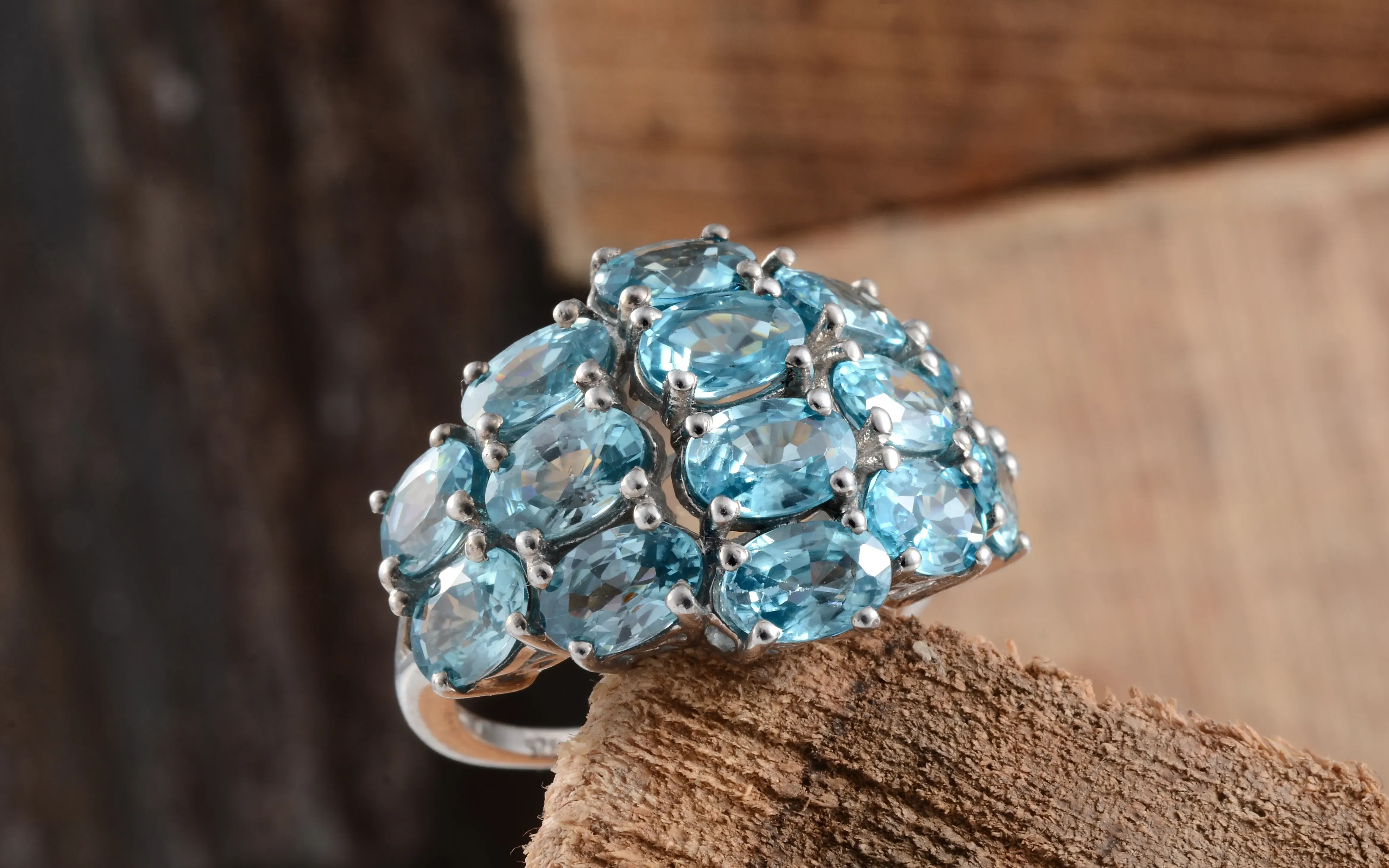 Blue zircon cluster ring on wooden stand.