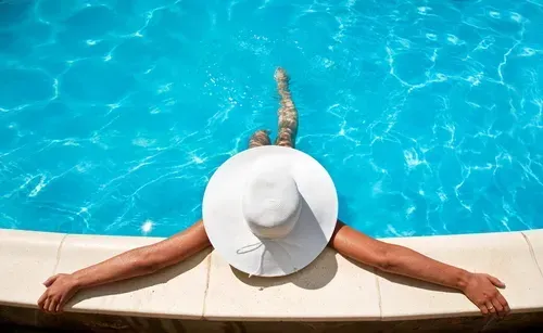 A woman in a floppy hat lounging in the pool.