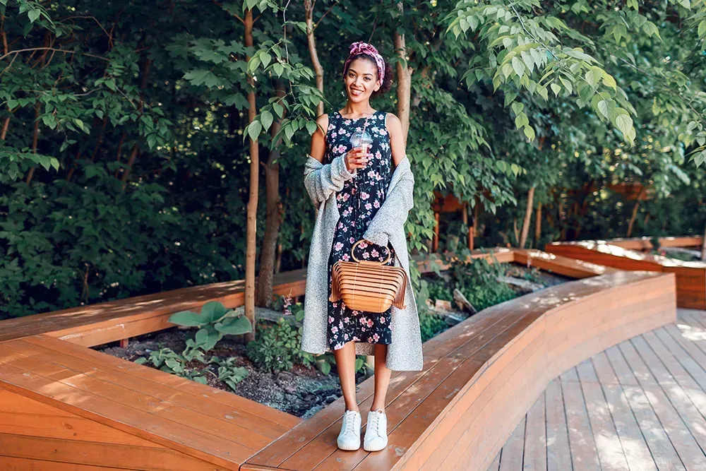 Woman wearing a dark floral dress with gray cardigan in the park
