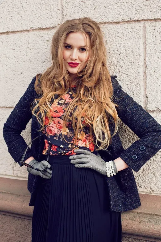 Woman wearing dark floral top with navy blazer and dark blue skirt