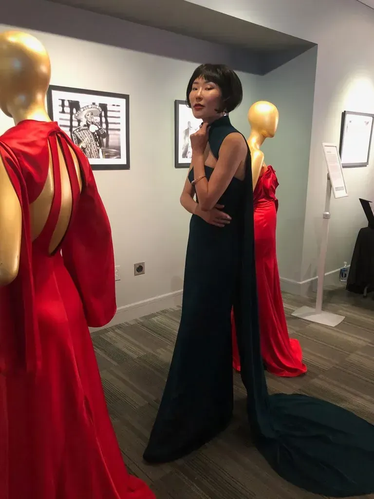 Asian model in a green dress showcasing Shop LC jewelry.