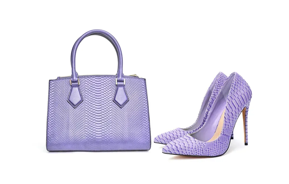Purple handbag with matching purple heels against white background