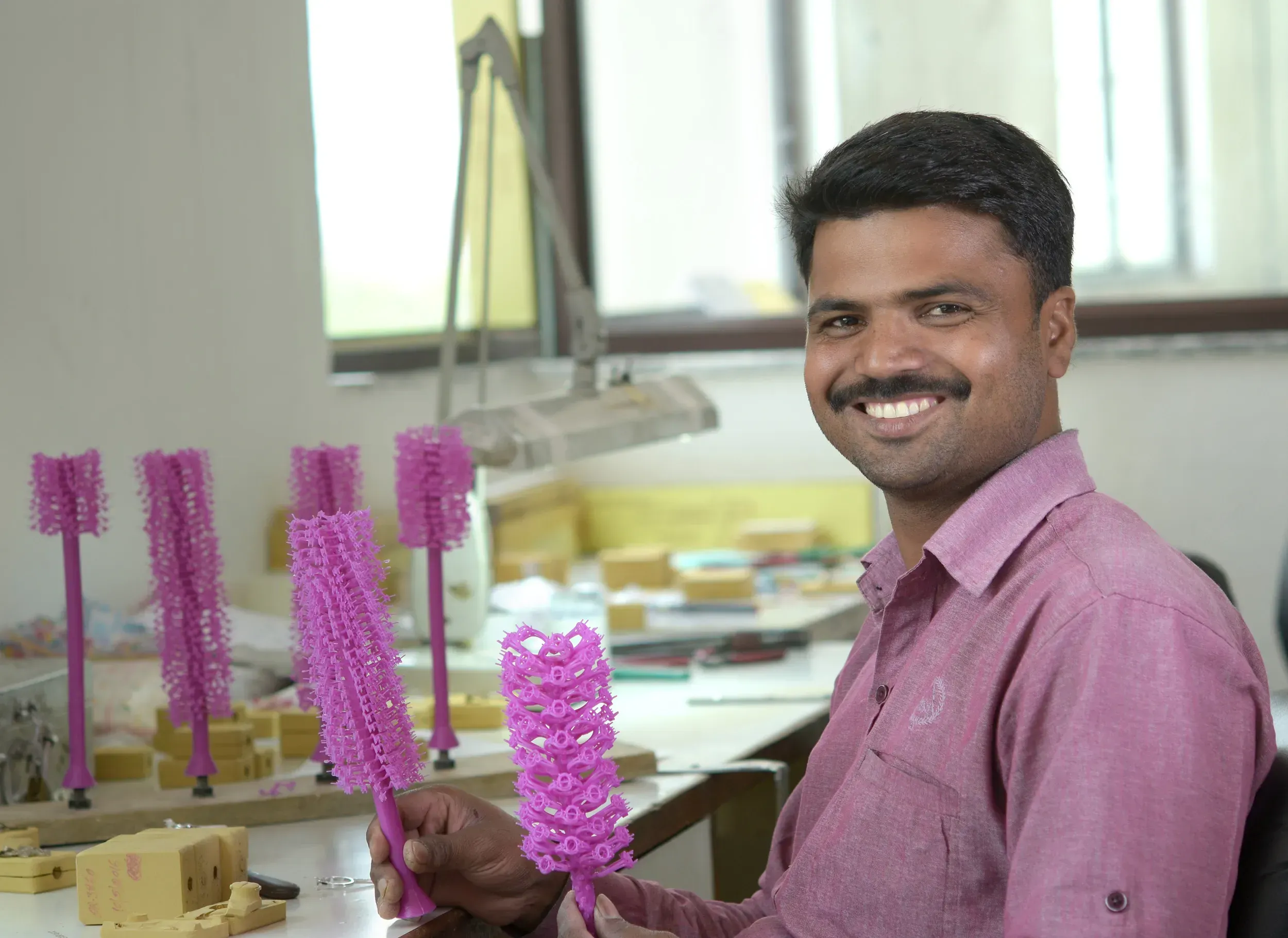 Worker displays a wax tree for jewelry molding.