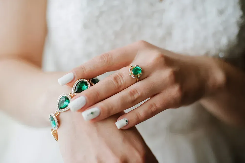 Closeup of woman with emerald ring and emerald bracelet