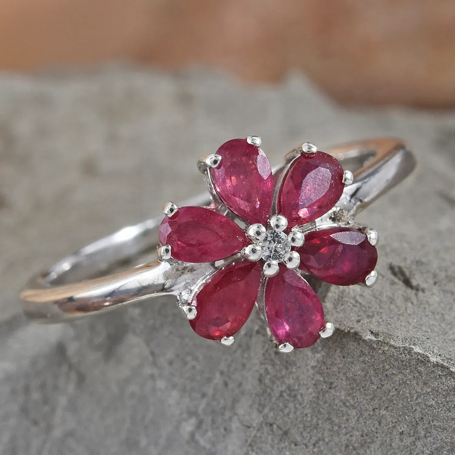 Floral ruby ring daintily resting on granite display.