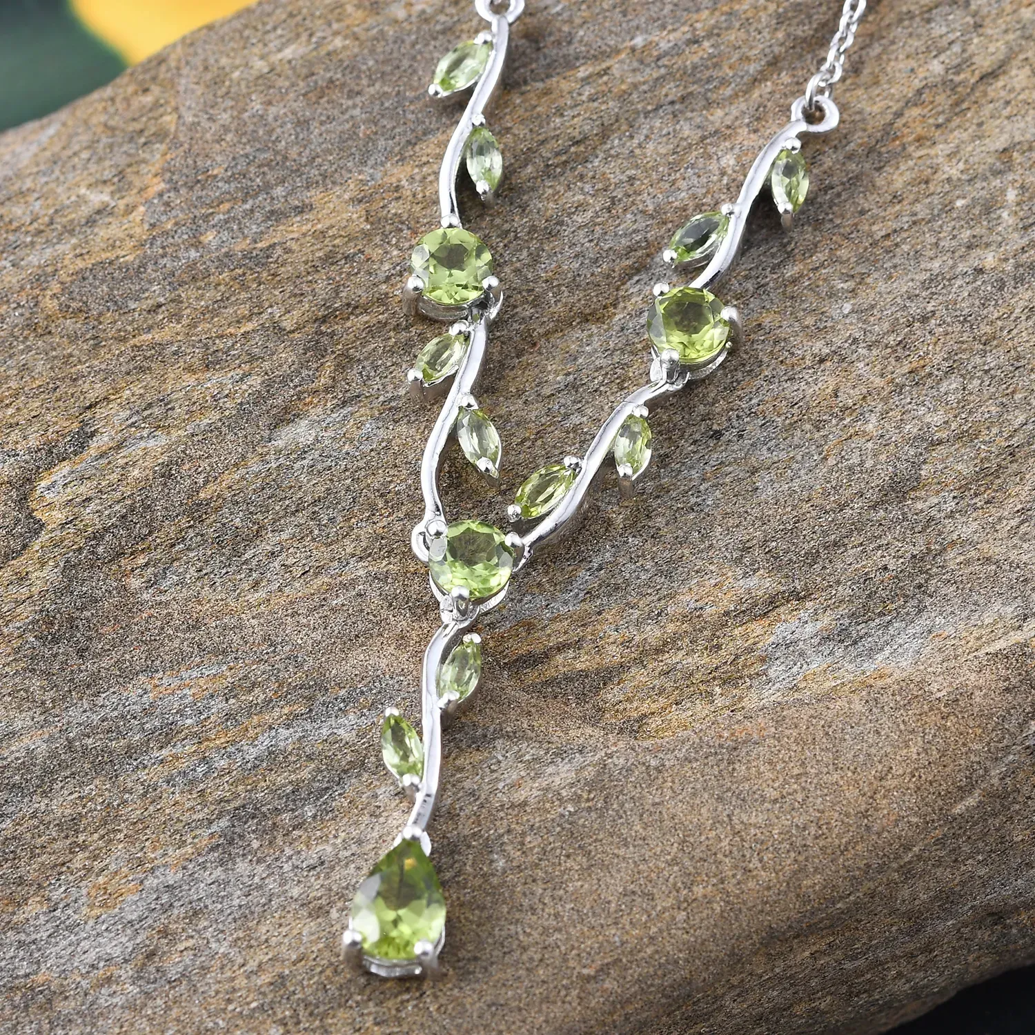 Peridot necklace carefully draped over stone.