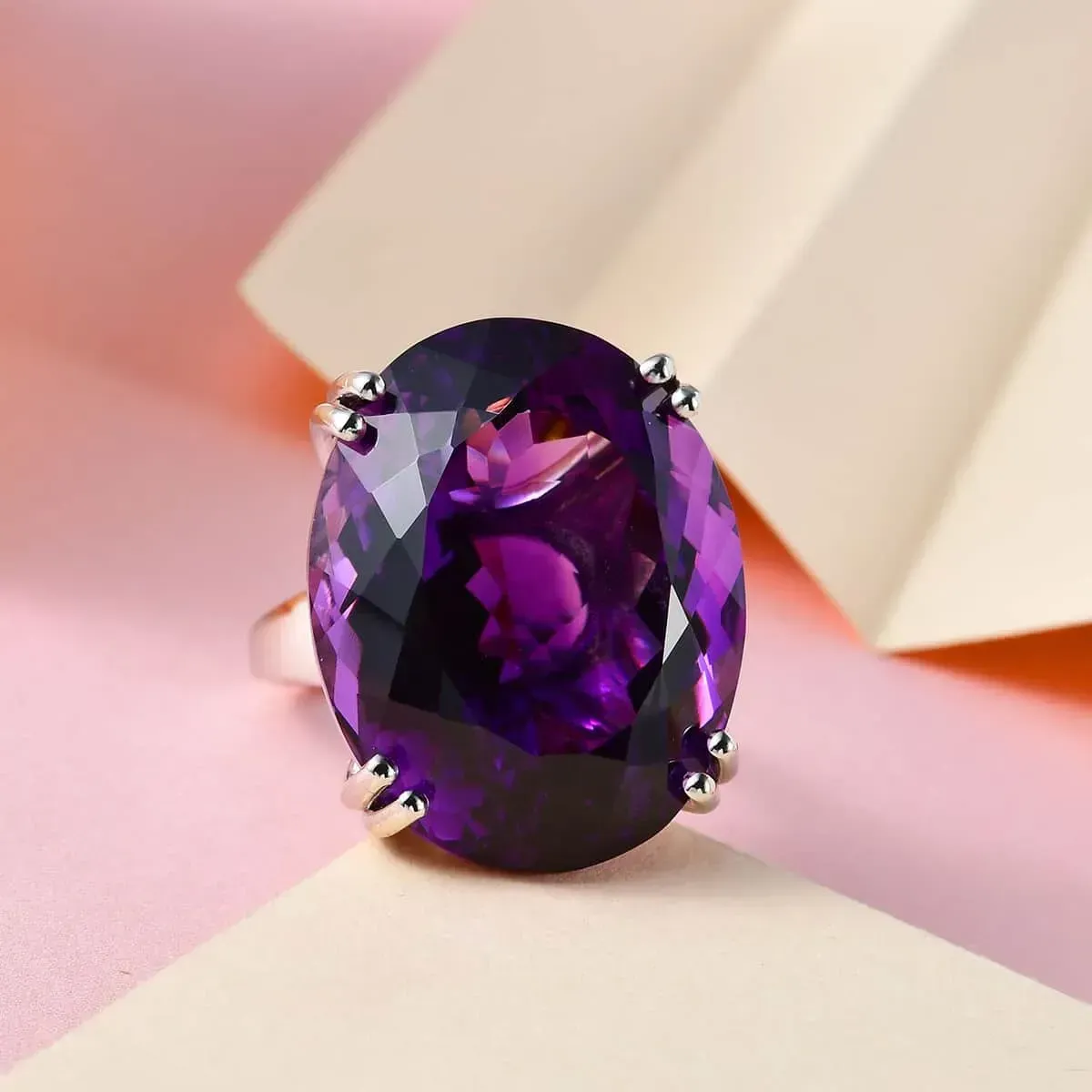African Amethyst Solitaire Ring in Platinum Over Sterling Silver against soft pink and cream background.