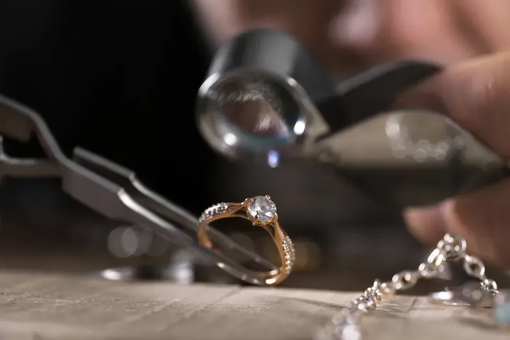 Male jeweler examining diamond ring in workshop, closeup view.
