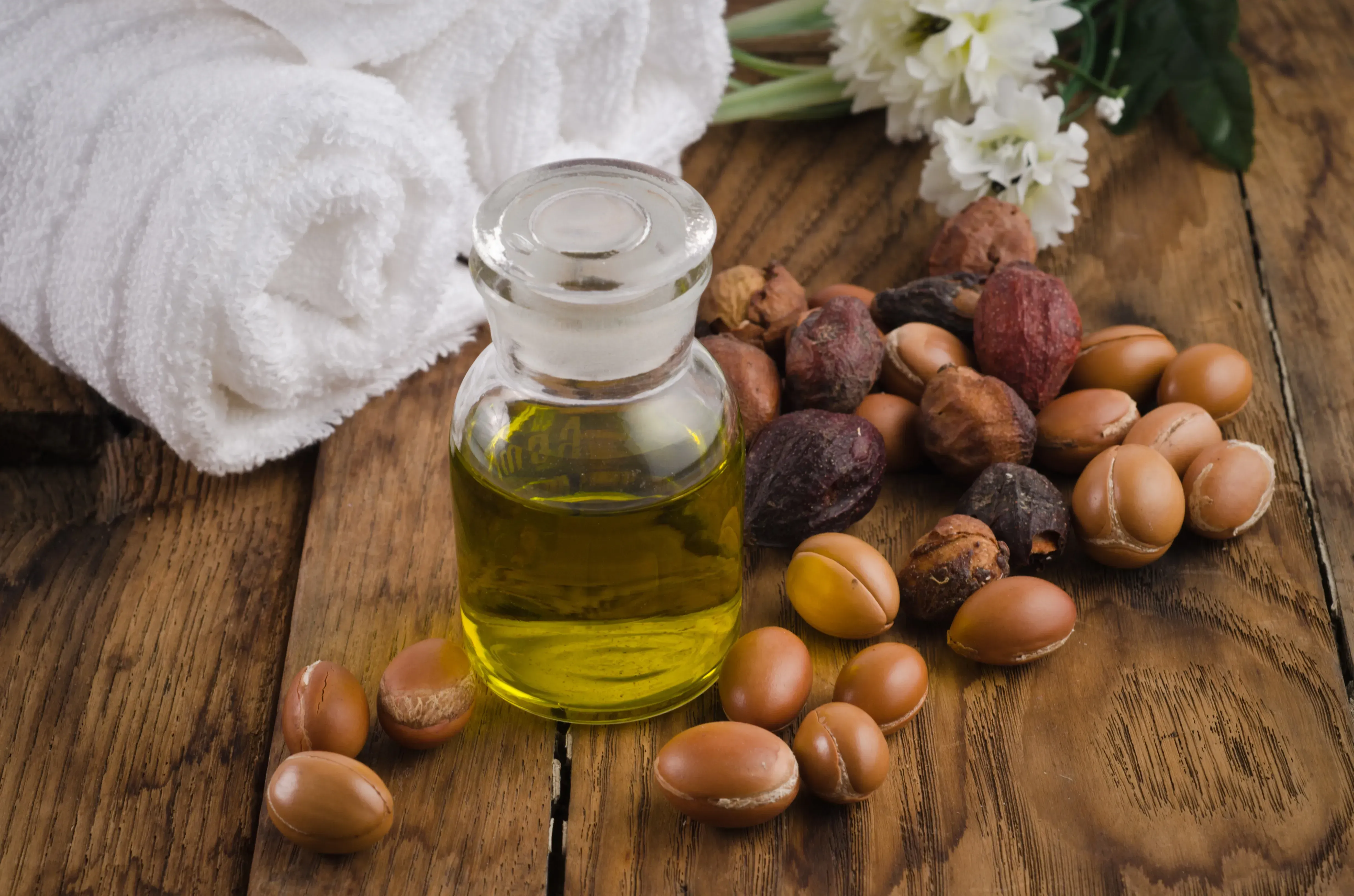Bottle of argan oil surrounded by argan fruit.