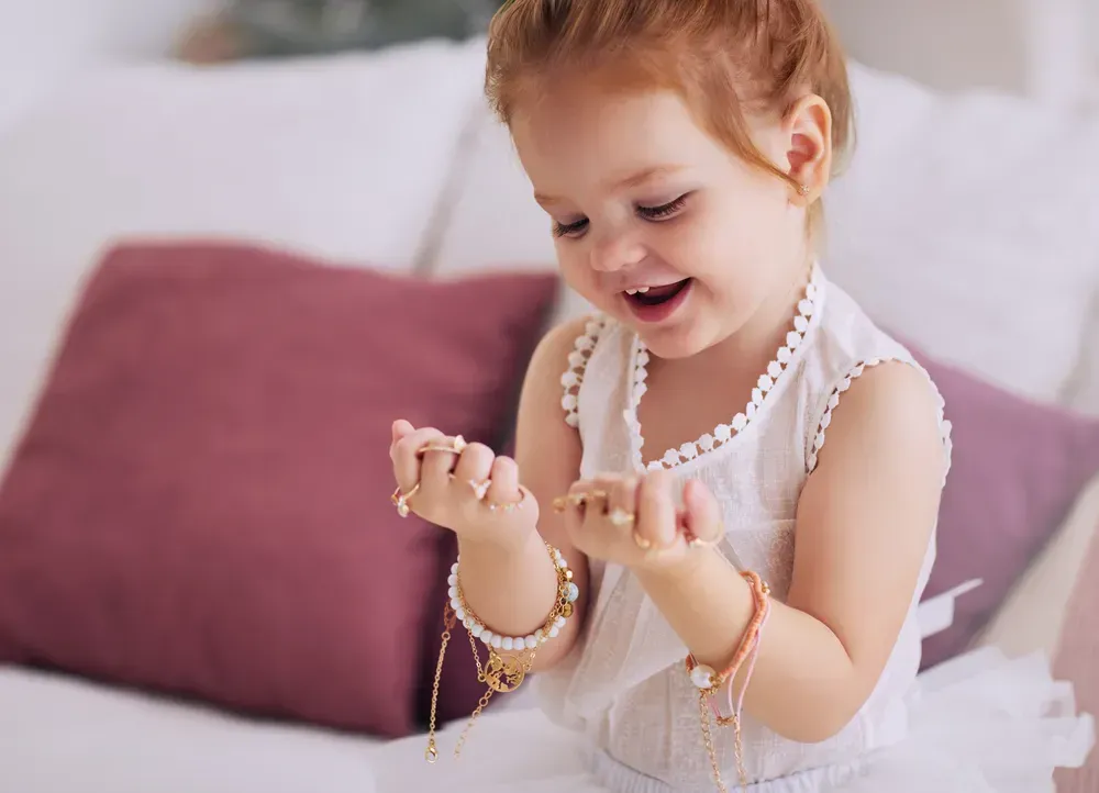 Smiling baby girl trying on grandma's jewelry.