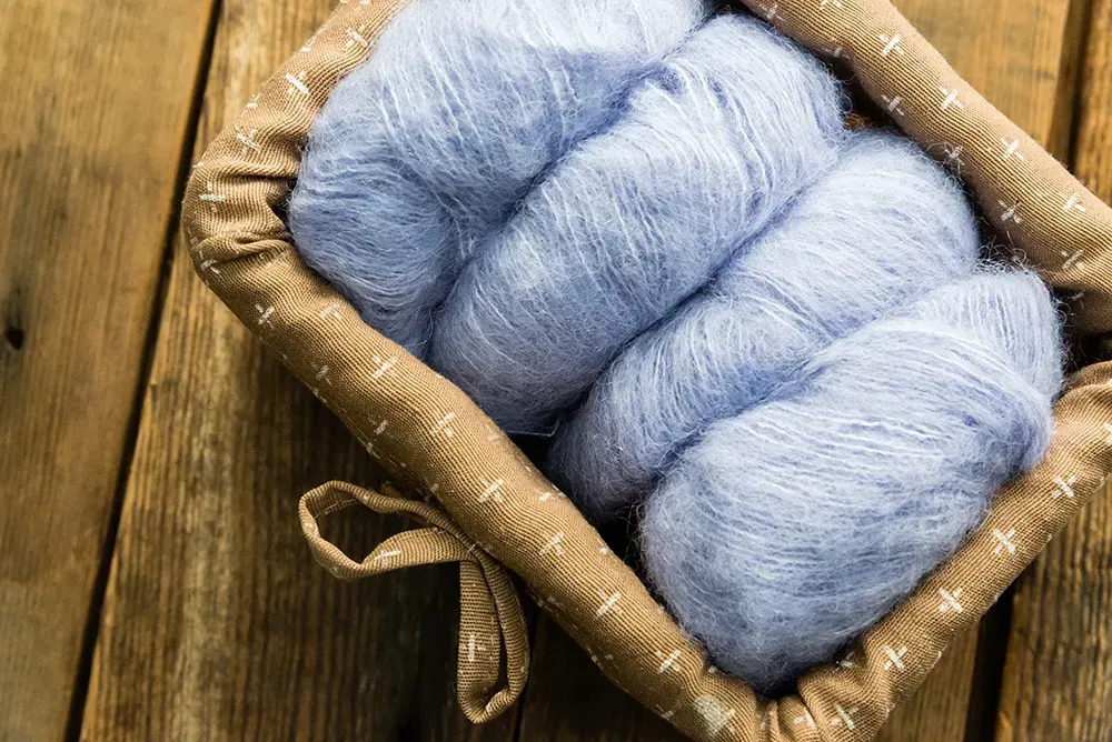 Light blue yarn in basket on wooden floor