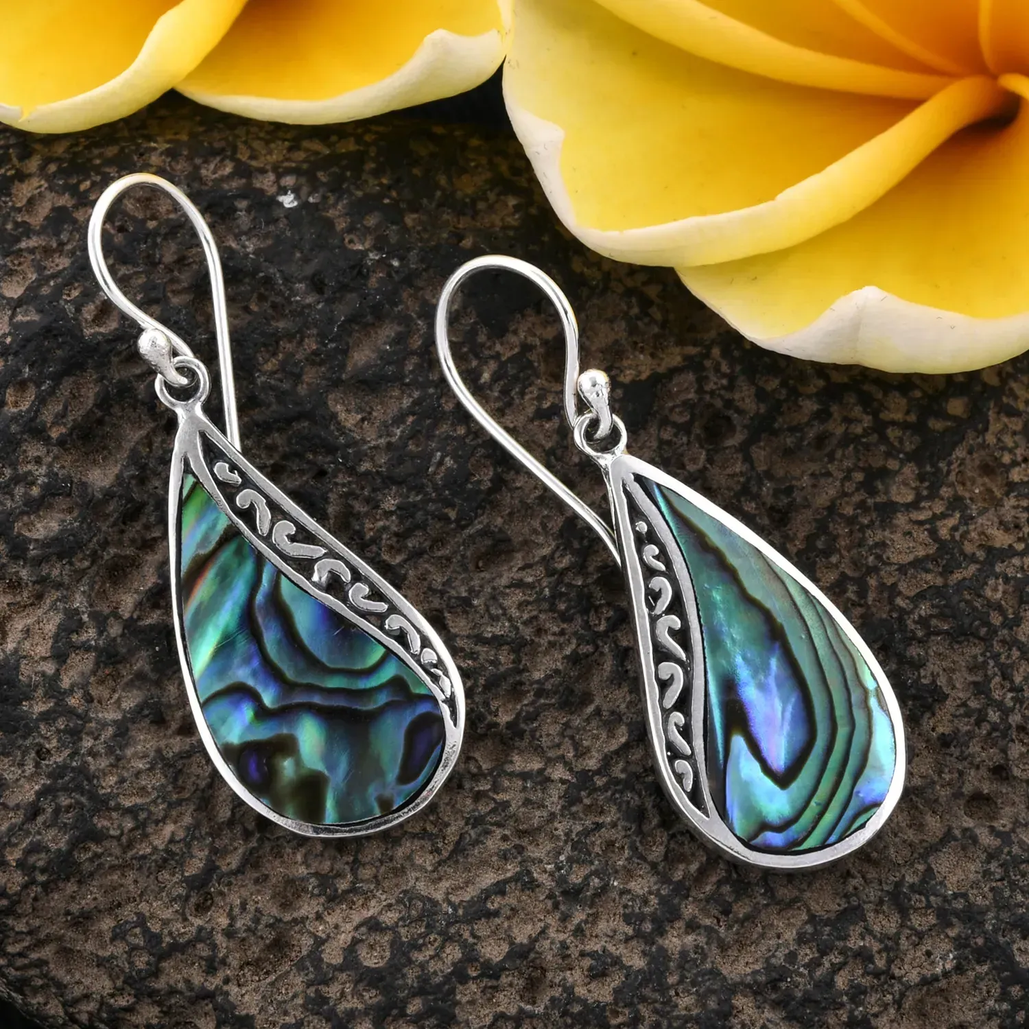 Abalone shell earrings on granite surface. 