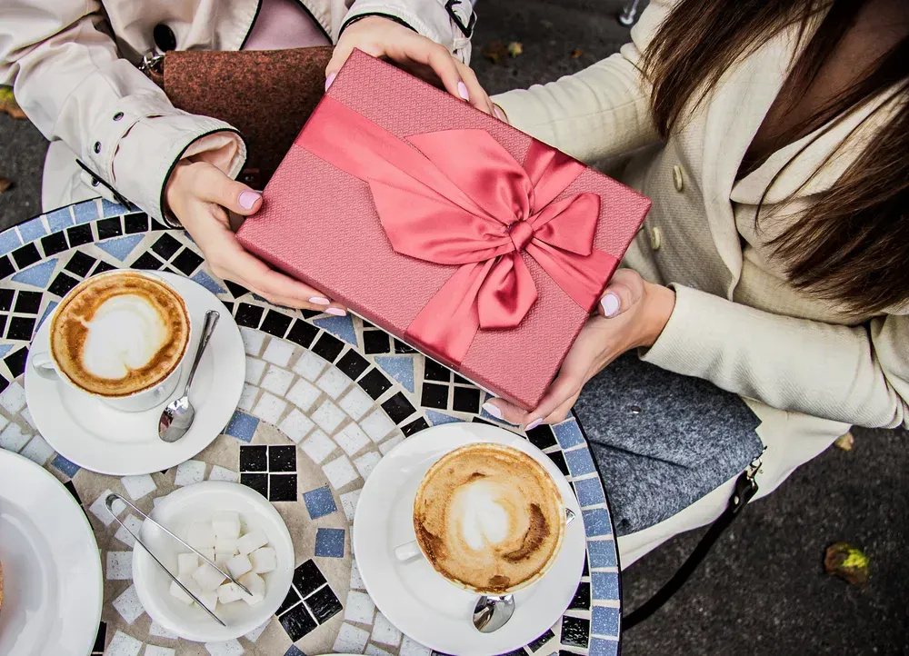 Top view of women exchanging presents while sitting in a vintage cafe. 