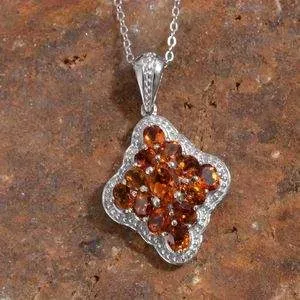 Citrine cluster pendant draped over red granite display board. 