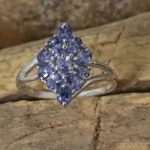 Artfully crafted tanzanite cluster ring displayed against natural wood. 