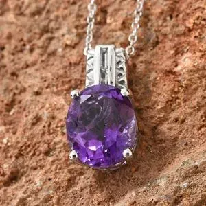 Amethyst pendant displayed against red stone. 