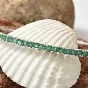 Emerald bangle displayed gracefully against sea shell.