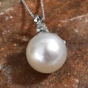 Pearl solitaire pendant displayed against red stone backdrop. 