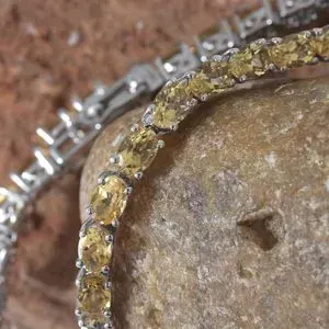 Citrine line bracelet draped on stone. 