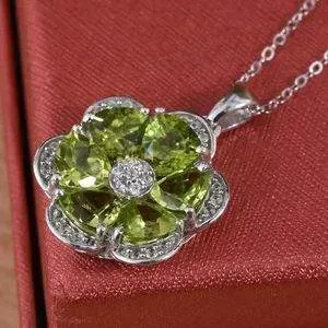 Peridot floral pendant resting on top of red silk box. 