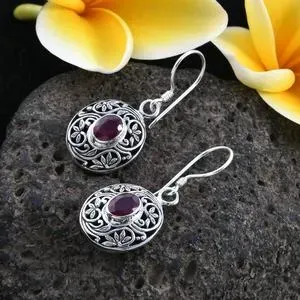 Ruby earrings in sterling silver against gray lava stone. 