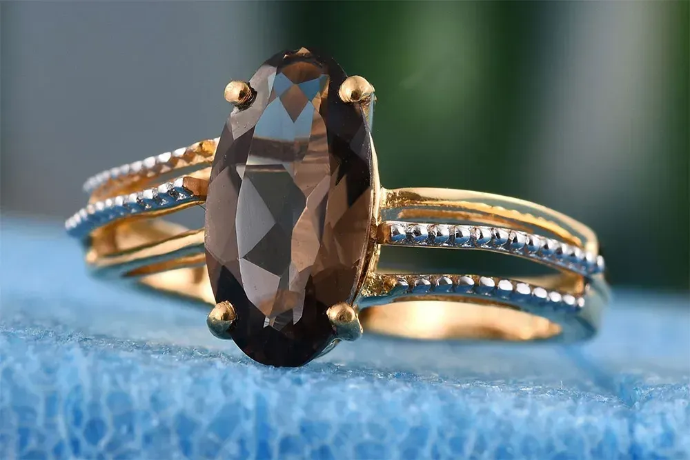 Oval smoky quartz ring against blue leather. 