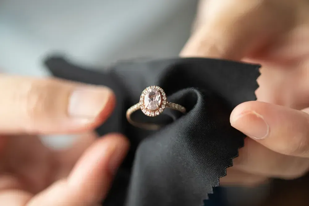 Jeweler cleaning jewelry diamond ring with fabric cloth.