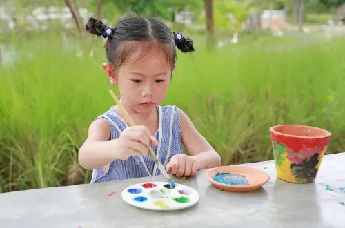 Girl painting plant pot. 