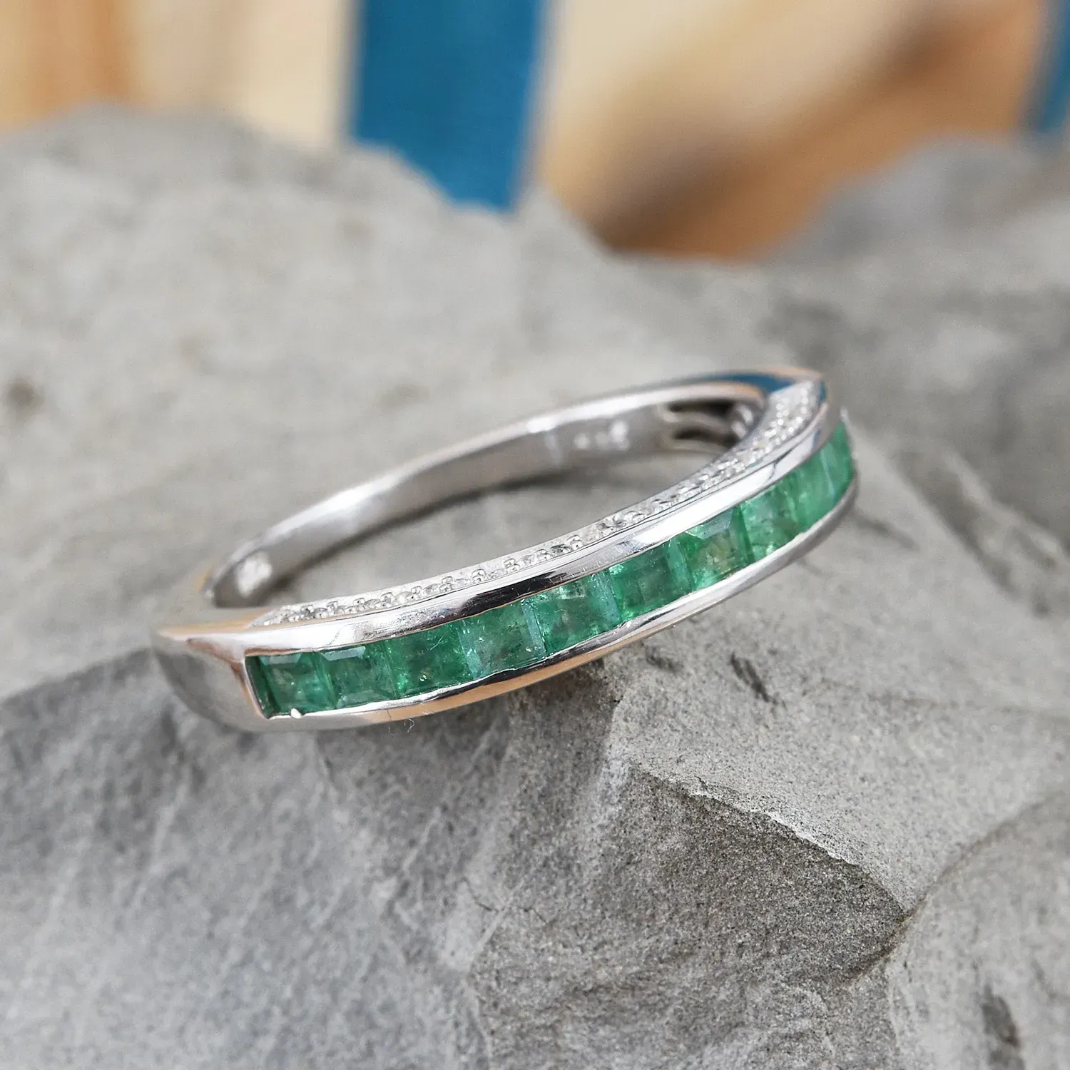 Emerald ring with channel set stones resting on slate Emerald ring with channel set stones resting on slate.
