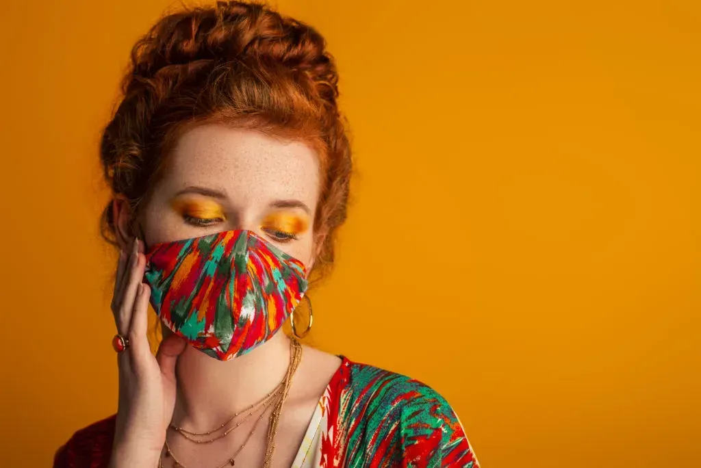 Woman in face mask with shimmery eye shadow.
