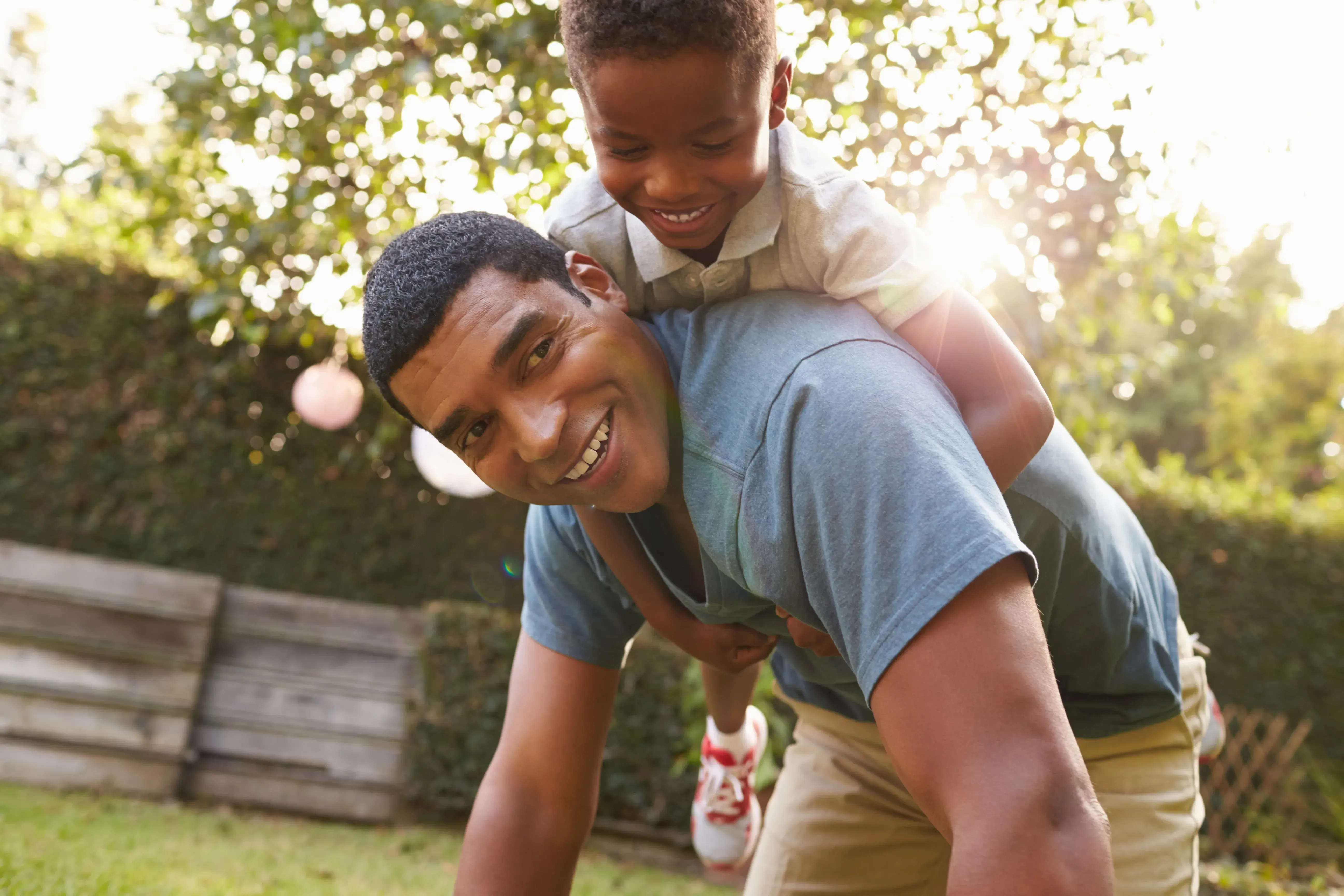 Father and son wrestling in the yard.