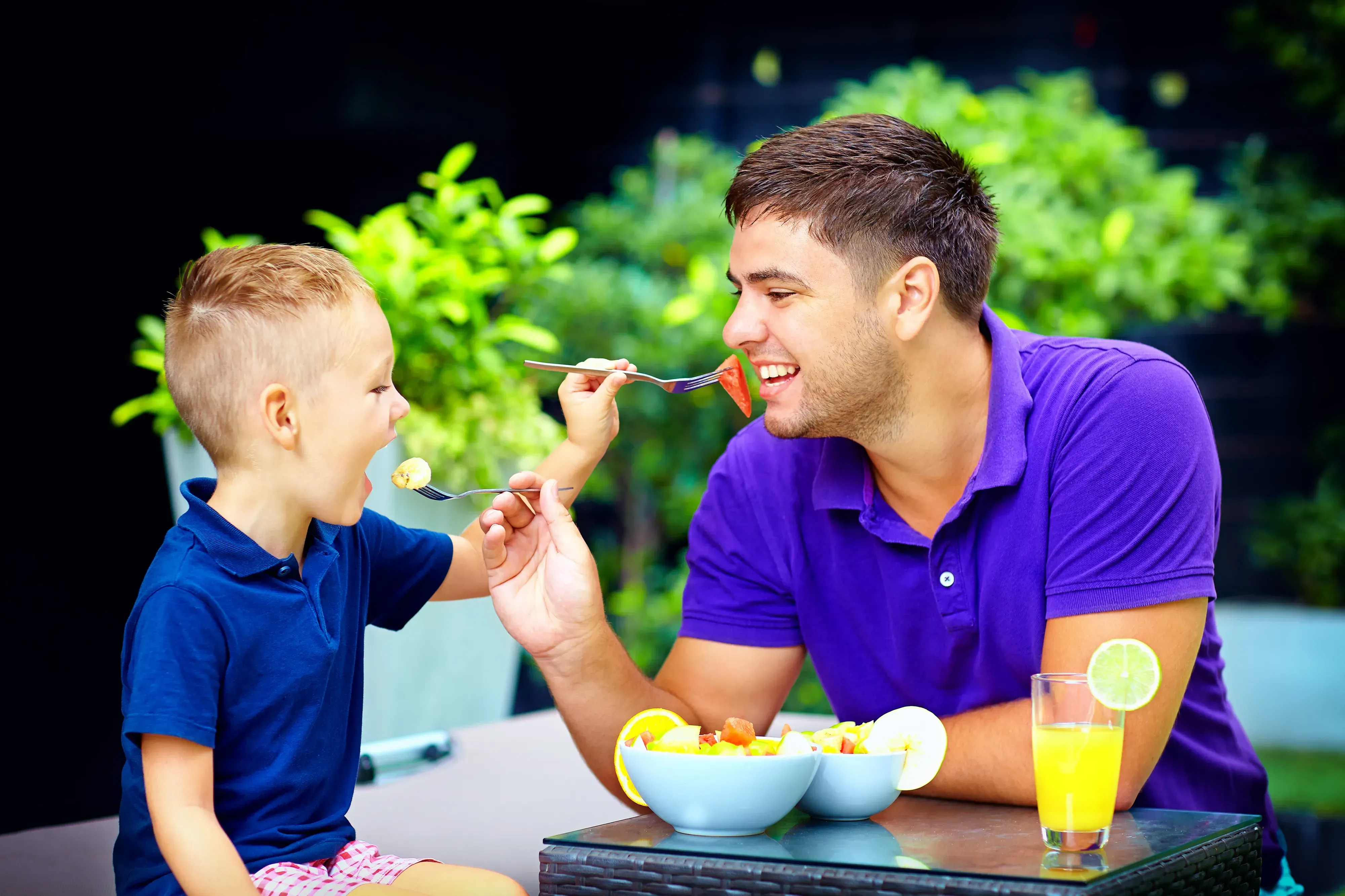 Father and son feeding each other a home cooked meal. 