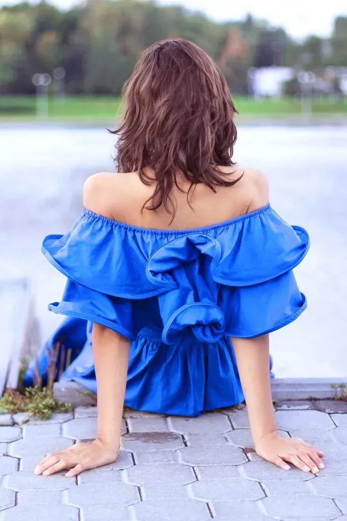 Woman wearing blue dress and sitting on steps.