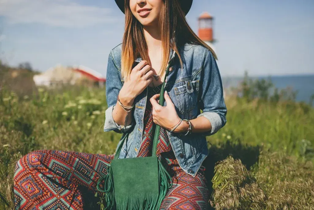 Woman in Bohemian outfit relaxing in plush, wild grass.