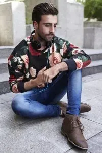 Man wearing black floral print shirt with denim pants.