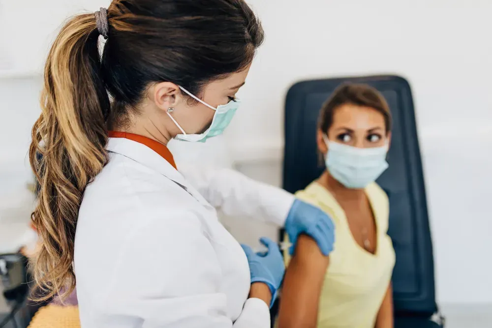 Female doctor giving flu shot to a patient's shoulder.