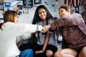Three friends fist bumping at a party.