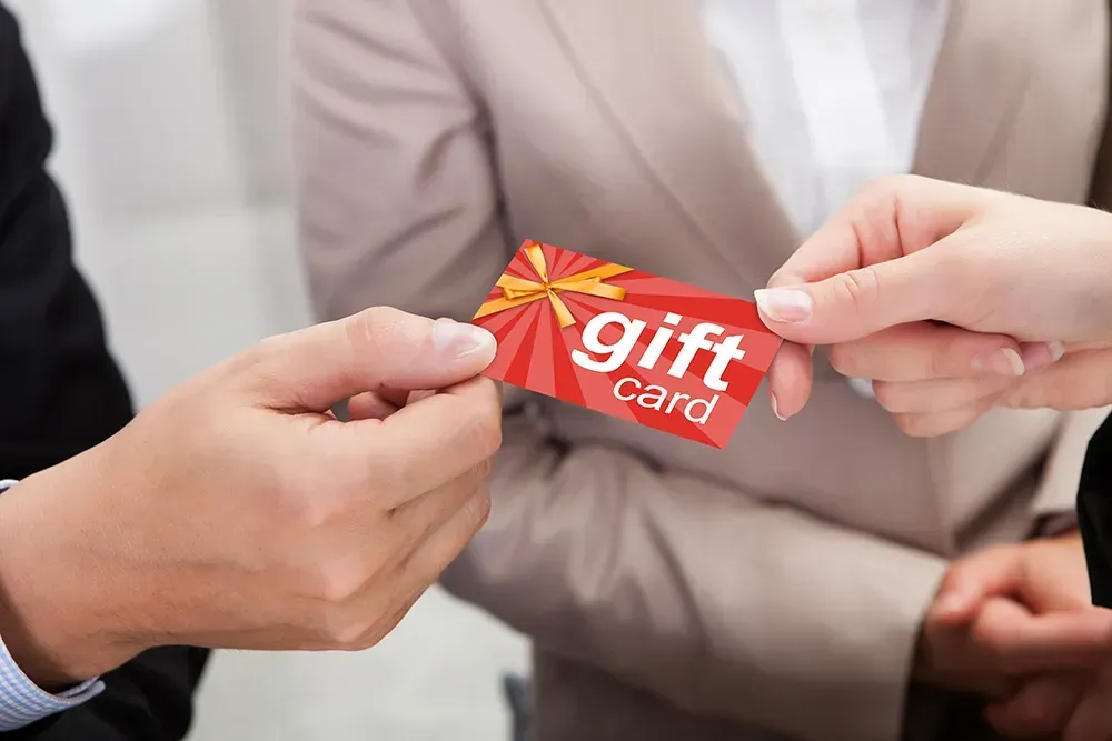 Closeup of man giving red gift card to wedding couple.