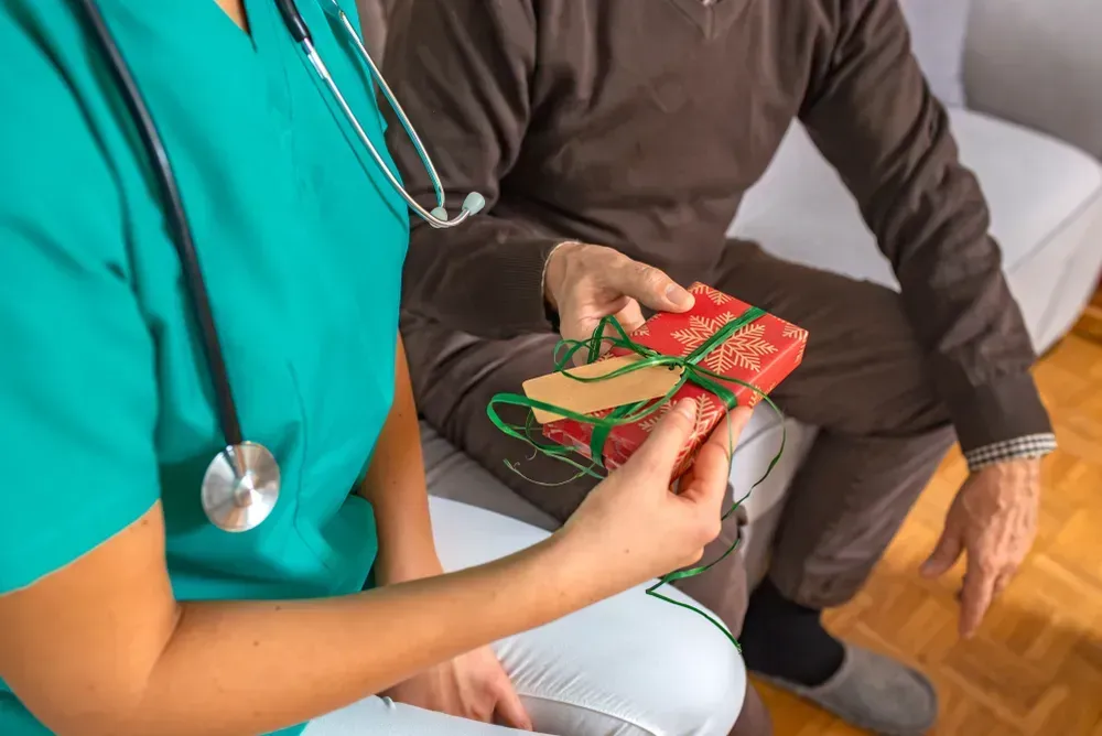 Grateful senior male patient giving a gift to his female doctor.