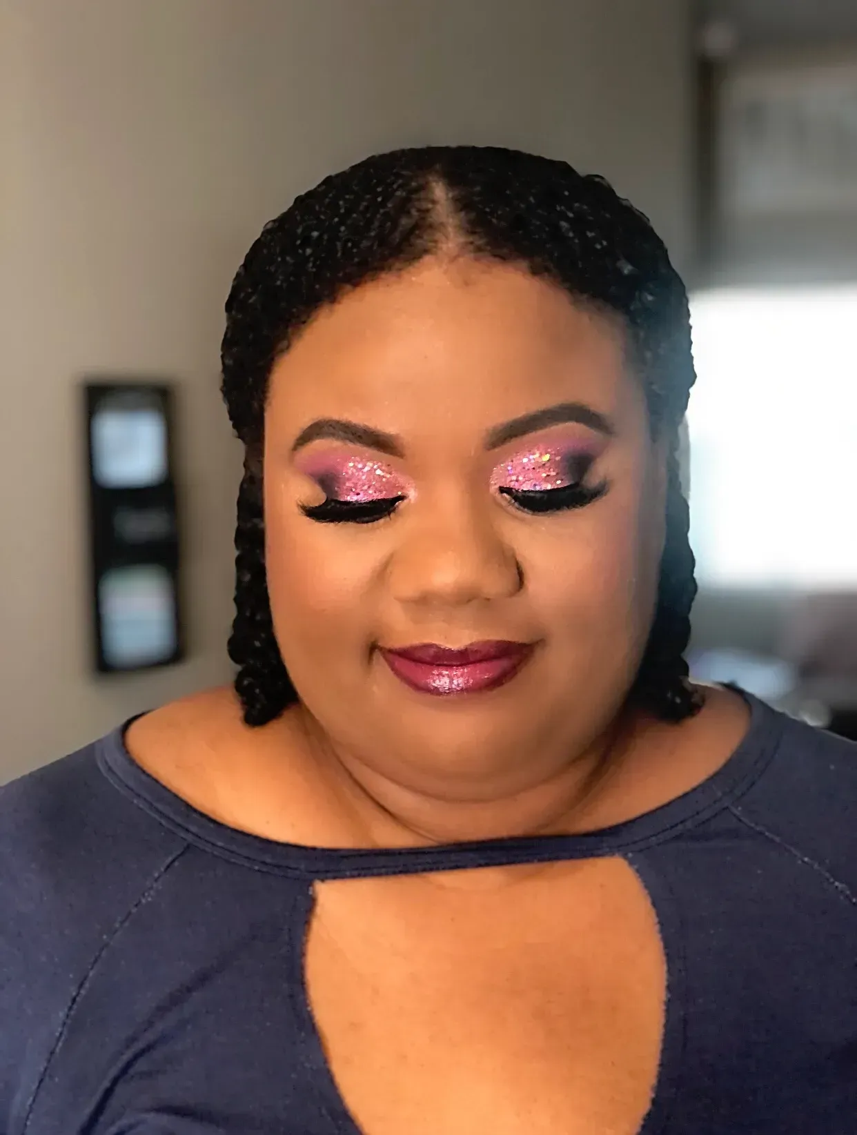 Woman with dark skin, showing glossy lip makeup.