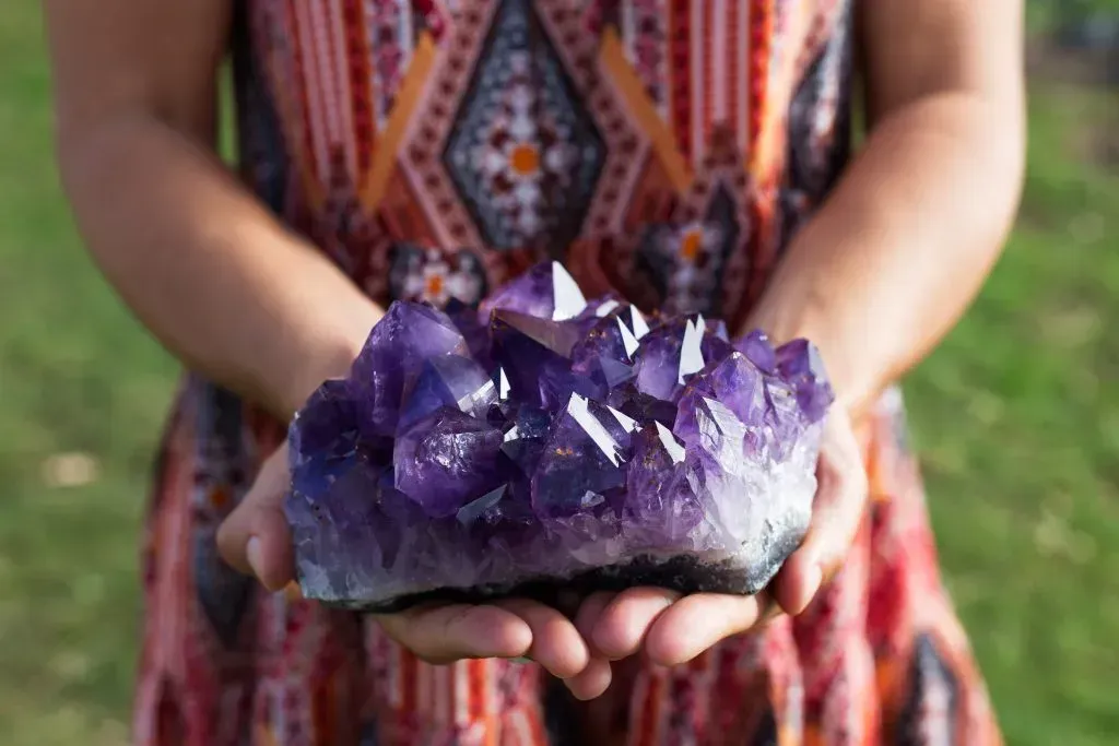Woman holding large amethyst sample. 