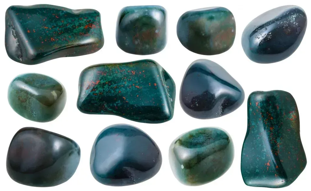 Eleven tumbled bloodstone gemstones on white background.