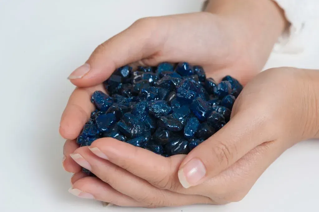 Two hands holding selection of blue sapphire rough.