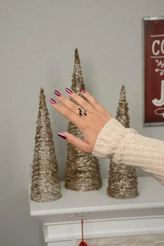 Woman admiring ring in front of holiday decorations.