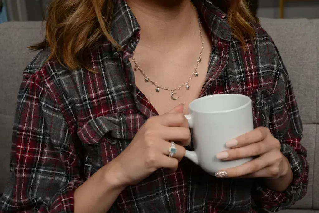 Woman in flannel shirt holding cup of hot cocoa.