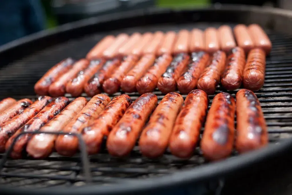 Cooking franks on a charcoal grill.