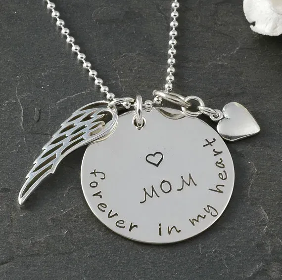 Closeup of silver necklace with engraved writing honoring a mother.