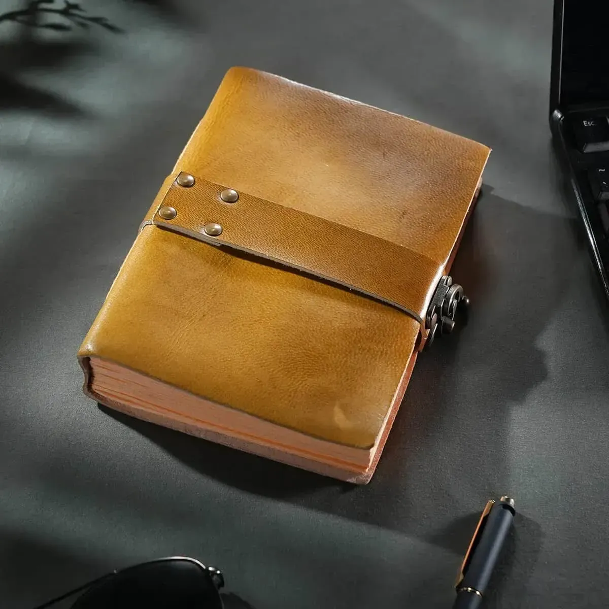 Yellow plain leather bound journal sitting on gray desk. 